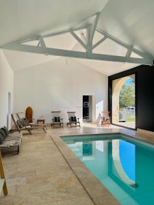 a swimming pool in a living room with a table and chairs at Château Bernon Gite 15 Personnes - piscine et SPA in Queyrac