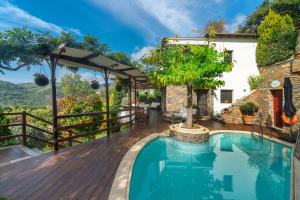 an outdoor swimming pool with a wooden deck and a house at Aenaon Villa with Private Pool Panoramic view in Miléai