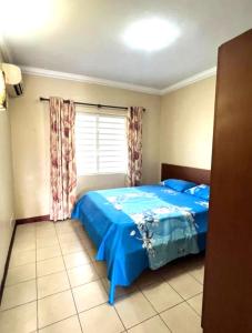 a bedroom with a blue bed and a window at Residence Les Peupliers 05-06 in Flic-en-Flac +9 photos