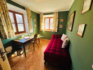 a living room with a red couch and a desk at VILLA SEEBERG - by "Schloss Gessenberg" luxurious vacation home with lake and mountain views, suitable for families and friends in Petting