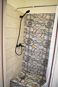 a bathroom with a shower with a stone wall at Alba - Open Plan Apartment in Artemida +21 photos