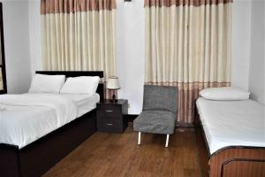 una camera con due letti e una sedia con tende di Shanti Apartment 2BHK Thamel 5 min walk 2nd Floor a Thapathali