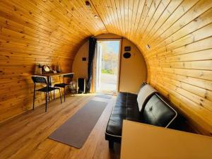 a living room with a black couch in a wooden wall at Woodside Round Pod in Fort William
