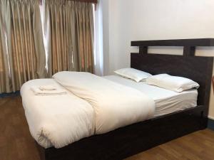 ThapathaliMakalu Apartment 2BHK Thamel 5 min walk 1st Floor的卧室里有一张铺着白色床单和枕头的床