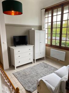 a bedroom with a bed and a tv and a dresser at Villa Millepertuis Bagnoles de l'Orne in Bagnoles de l'Orne