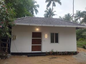 a small white house with a window and a door at Katadi beach coral cottage in Thanniyam