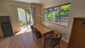 a kitchen with a wooden table and chairs and a window at Mimosa Cottage in Cape Town