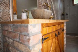 a bathroom with a sink on a brick wall at Privát Szálláshely Dézsafürdővel-Kata Cottage in Szanda +12 photos