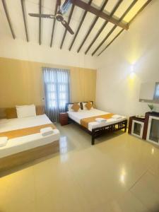 a large room with two beds and a window at Chrish Residence in Negombo