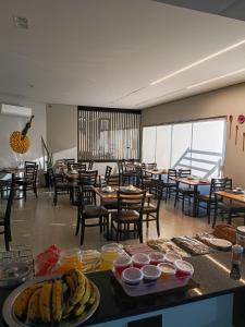ein Restaurant mit Tischen, Stühlen und Speisen auf einem Tisch in der Unterkunft Hotel Maranhão in Ourinhos