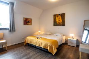 a bedroom with a bed with a yellow blanket at Het Maashotel in Broekhuizen