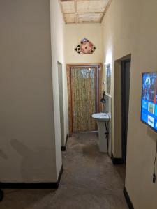 un couloir avec une salle de bain avec un lavabo et une télévision dans l'établissement Akagera Homestay Experiences, à Rwinkwavu
