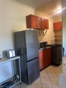 Una cocina con refrigerador de acero inoxidable y gabinetes de madera. en Unit 2B Sun And Surf, en KwaDukuza