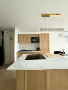 a kitchen with a white counter top and wooden cabinets at L'Ukiyo-e - Vue Mer et Sauna by Alto Service in Le Barcarès