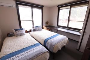 two beds in a room with two windows at Forest and Stars Akakura Luxe in Myoko