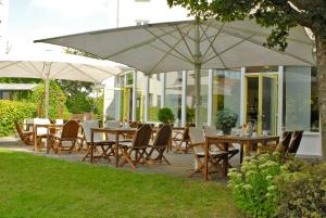 レーゲンスブルクにあるハンザ アパート-ホテル レーゲンスブルクの傘の下に置かれたテーブルと椅子のグループ
