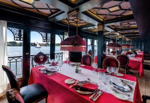 Un vagón comedor de un barco con mesas y sillas rojas. en Movenpick SS Misr Steamer Nile Cruise - 04 & 07 Nights Each Monday From Luxor and 03 Nights Each Friday from Aswan, en Luxor