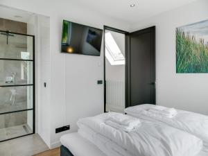 Cette chambre blanche dispose de 2 lits et d'une télévision. dans l'établissement Great holiday home energy neutral on Texel with sauna and sun shower, à Westermient