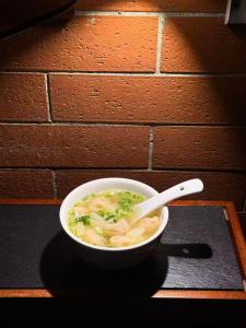 a bowl of noodle soup with a spoon on a table at Nostalgia Hotel Beijing Yonghe Lama Temple in Beijing
