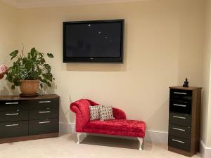 ein Wohnzimmer mit einem roten Stuhl und einem TV an der Wand in der Unterkunft Meadow Farm in Royal Wootton Bassett + 12 Fotos