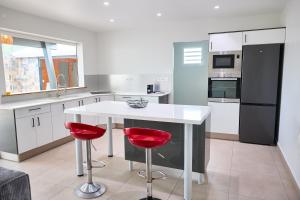 a kitchen with a white table and two red bar stools at Écrin d'évasion in Sainte-Anne +7 photos