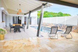 a patio with a table and chairs and a pool at Écrin d'évasion in Sainte-Anne