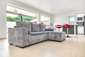 a living room with a gray couch and a red lamp at Écrin d'évasion in Sainte-Anne