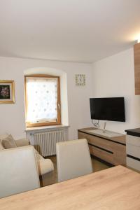 un soggiorno con TV, tavolo e sedie di Appartamento Margherita a Panchia