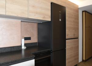 una cucina con elettrodomestici neri e armadietti in legno di Appartamento Margherita a Panchia Altre 8 foto