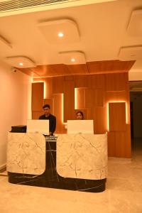 dwoje ludzi siedzących przy biurku z laptopami w obiekcie The Regal Crown By Ritya Hotels w mieście Ayodhya