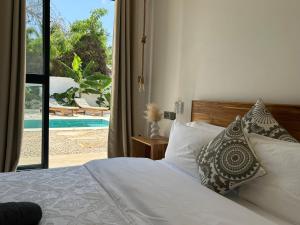 a bedroom with a bed and a view of a pool at U Paradisu Villas-Jambiani in Kibigija +25 photos