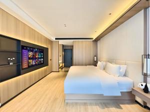 Un dormitorio con una cama grande y un televisor de pantalla plana. en Jingyue International Hotel Chengdu Tianfu International Airport Branch, en Jiangyang