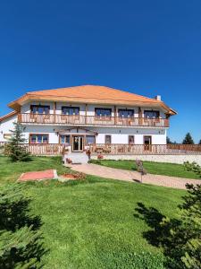a large white house with a large yard at Pensiunea Roua Brazilor Mărișel in Mărişel