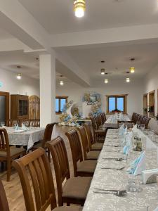 a dining room with a long table and chairs at Pensiunea Roua Brazilor Mărișel in Mărişel +28 photos