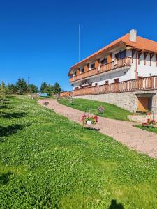 a building with a balcony on top of a green field at Pensiunea Roua Brazilor Mărișel in Mărişel