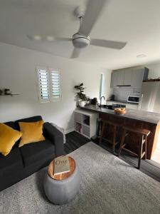 a living room with a black couch and a kitchen at Wollongong Tiny Home in Coniston