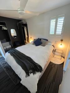 a bedroom with a large bed with white sheets and blue pillows at Wollongong Tiny Home in Coniston