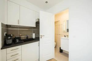 eine Küche mit weißen Schränken und einer Spüle in der Unterkunft Appartement moderne & cosy Suresnes in Suresnes