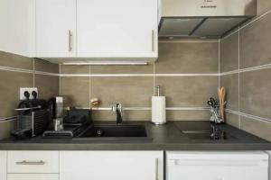 eine Küche mit Spüle und weißen Schränken in der Unterkunft Appartement moderne & cosy Suresnes in Suresnes