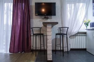 a bar with three stools and a tv on a wall at Exclusive apartment at the in Mykolaiv
