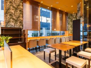 東京にあるアパホテル＜銀座京橋南＞（東京駅八重洲南）の木製のテーブルと椅子と窓のあるレストラン