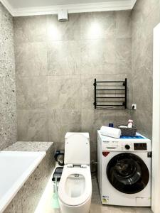 ein Badezimmer mit Waschmaschine und Toilette in der Unterkunft Светлая и уютная квартира с видом на горы, рядом с ТРЦ in Almaty