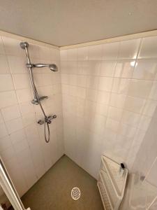 a shower in a white tiled bathroom with a drain at M & M home in Karlshamn +22 photos