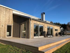 una casa con una gran terraza de madera frente a ella en Stunning, modern home with a lakeview, en Äspered