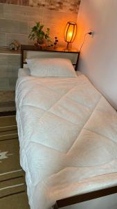 ein großes weißes Bett in einem Zimmer mit einer Lampe in der Unterkunft Simple home in Madaba