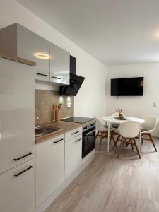 Smart Home Bad Camberg - moderne Ferienwohnung في باد كامبيرغ: مطبخ مع دواليب بيضاء وطاولة طعام