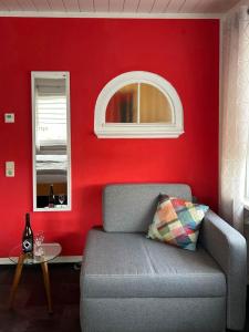 a living room with a couch and a red wall at Ferienwohnung Vicus - am Fuße des Schaumberges in Tholey
