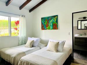 zwei Betten in einem Zimmer mit einem Gemälde an der Wand in der Unterkunft Finca Bella Village Para Amantes del Entorno Rural in Jiguales