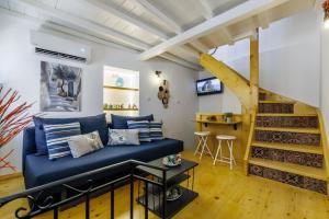 a living room with a blue couch and a staircase at Maritina Skopelos Maisonette in Skopelos Town