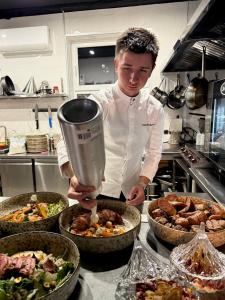 un chef de pie en una cocina preparando comida en Gloria Hotel by YOLO, en Szack